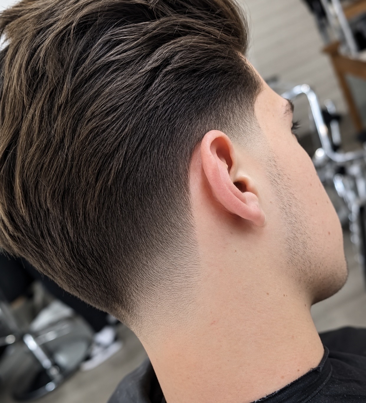 Longer textured haircut blending into a clean fade around the ear and neckline